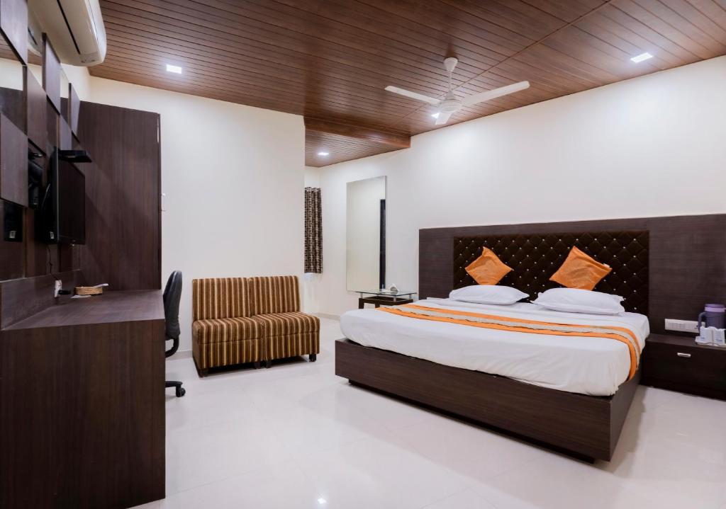a hotel room with a bed and a chair at Hotel Ashish in Ahmedabad