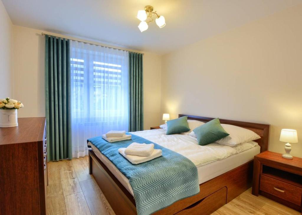 烏斯奇基的住宿－Apartament Zielony Zakątek，一间卧室设有床铺和一个带绿色窗帘的窗户。