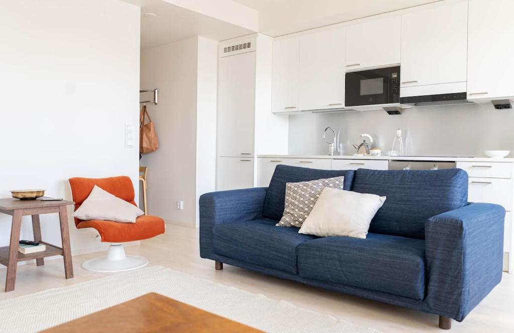 uma sala de estar com um sofá azul e uma cozinha em Stylish new 1br apt in Aurinkolahti em Helsinque