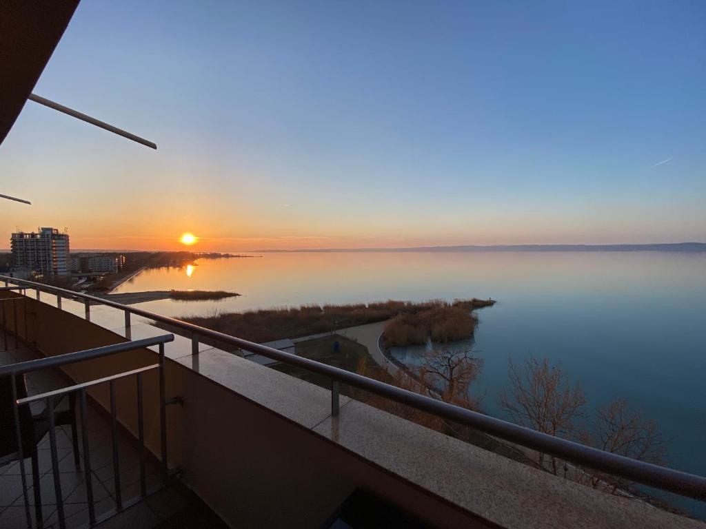a view of a lake at sunset from a balcony at MyFlat Club 218 Golden Beach Wellness Apartment in Siófok