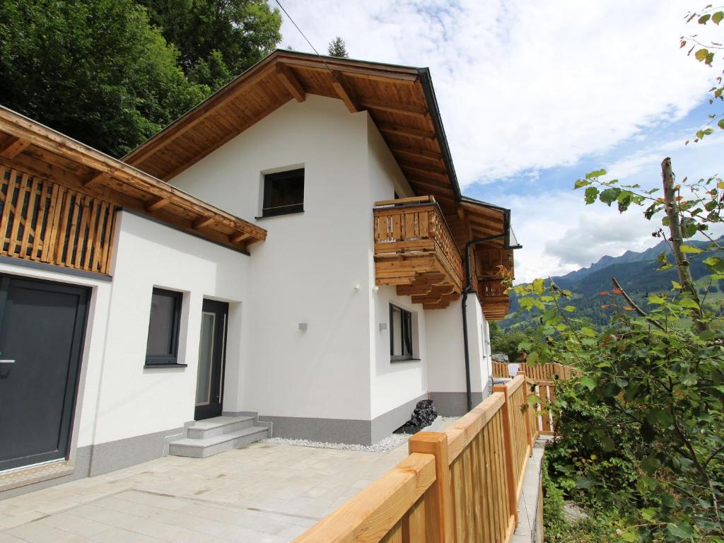 une maison dans les montagnes avec une clôture en bois dans l'établissement Chalet in Bruck am Grossglockner near ski lift, à Bruck an der Großglocknerstraße