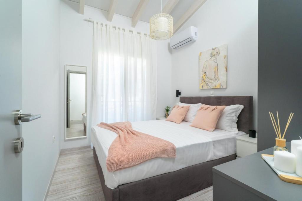 een witte slaapkamer met een bed met roze kussens bij Terra Mare in Skala Potamias