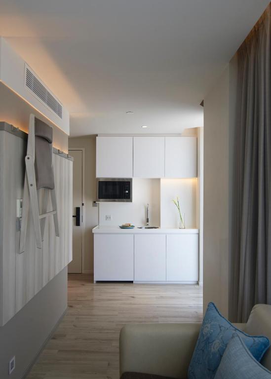 A compact kitchenette viewed from the sofa area of a studio room.