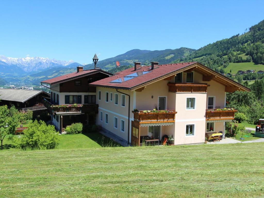 a house on top of a hill with mountains in the background at Large flat close to the ski area in Sankt Veit im Pongau