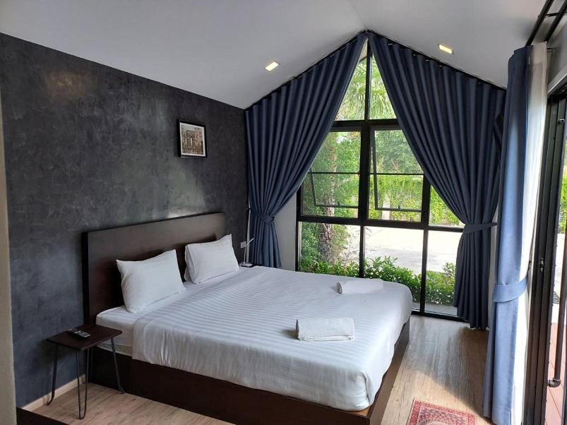 um quarto com uma cama grande e uma janela grande em The Sept Korat em Nakhon Ratchasima