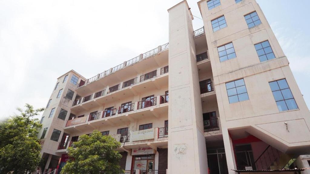 a tall white building with balconies on it at Hotel Mohan by WB INN in Agra