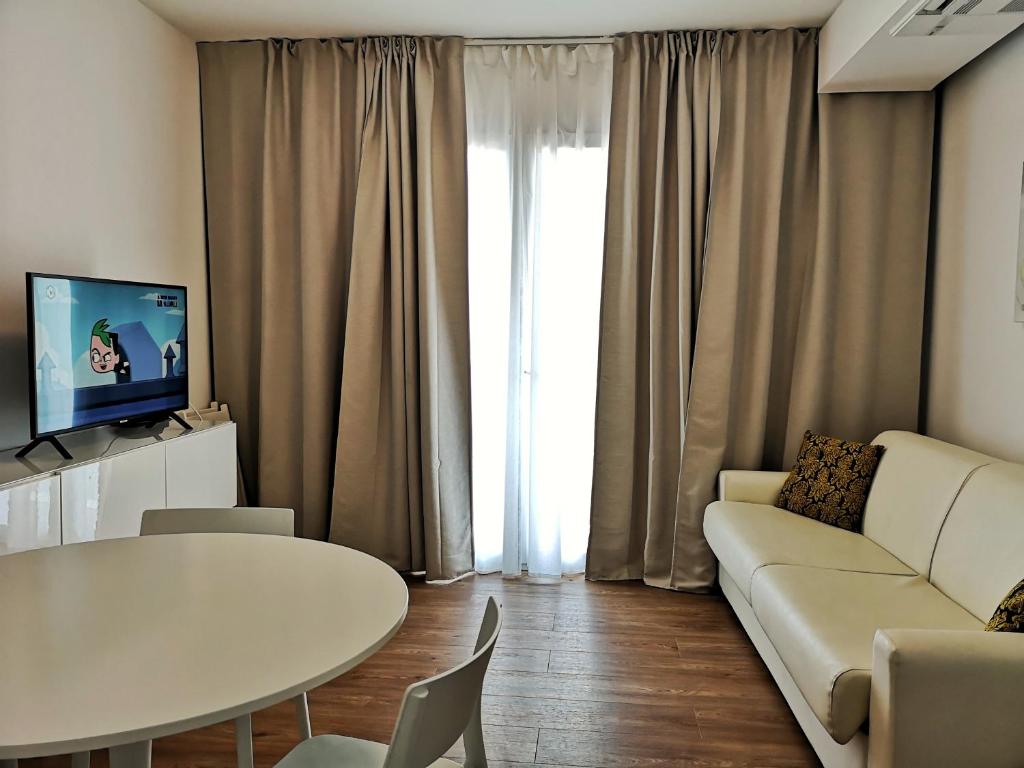 een woonkamer met een witte bank en een tafel bij Family Suite Appartments Orchidea Blu in Rimini