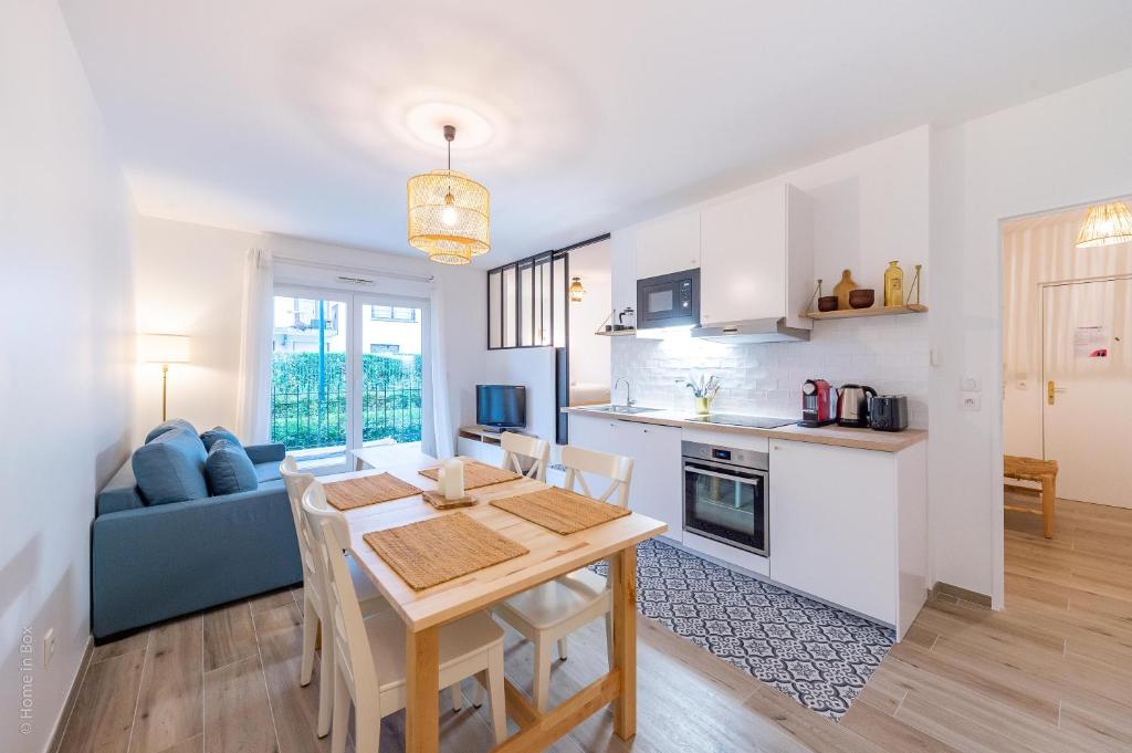 Il dispose d'une cuisine et d'un salon avec une table et des chaises en bois. dans l'établissement Woody Cocon by Plaza - Proche Disneyland Paris, à Montévrain