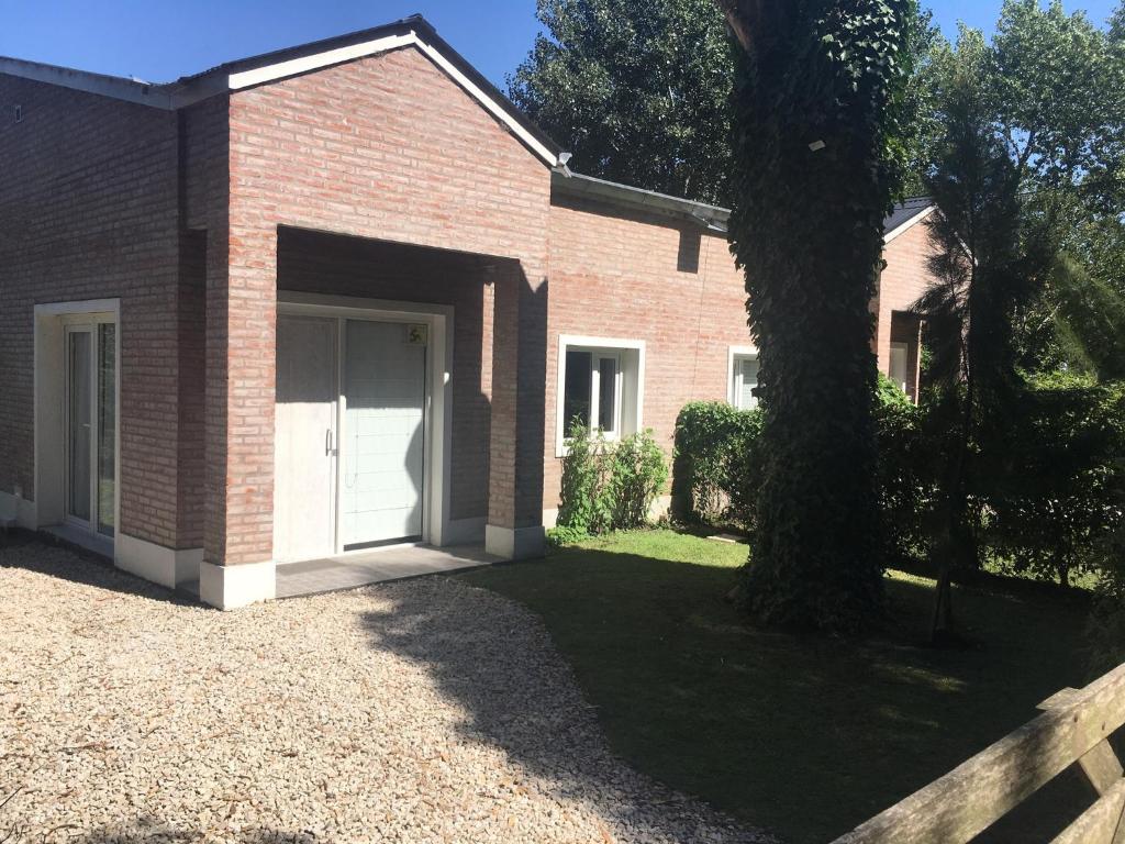 a brick building with a white door next to a tree at Duplex Las Margaritas Bosque Peralta Ramos in Mar del Plata