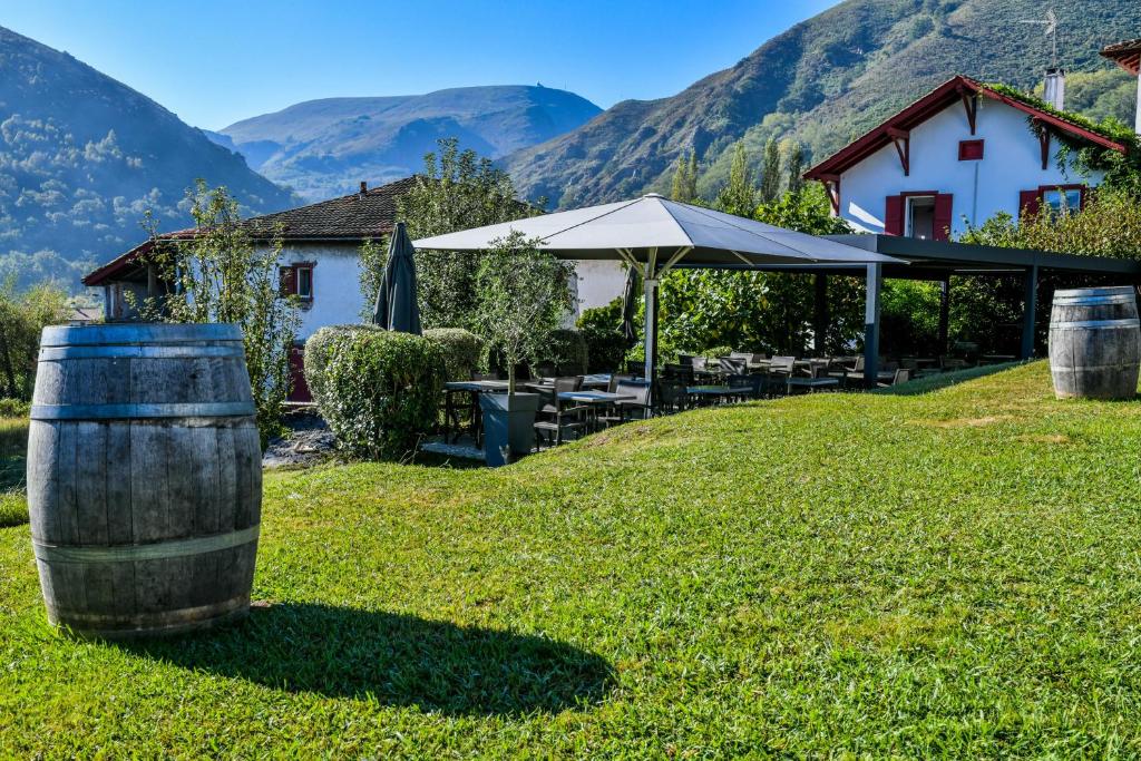 una casa con un barril en la hierba con montañas en Logis Hôtel du Chêne, en Itxassou