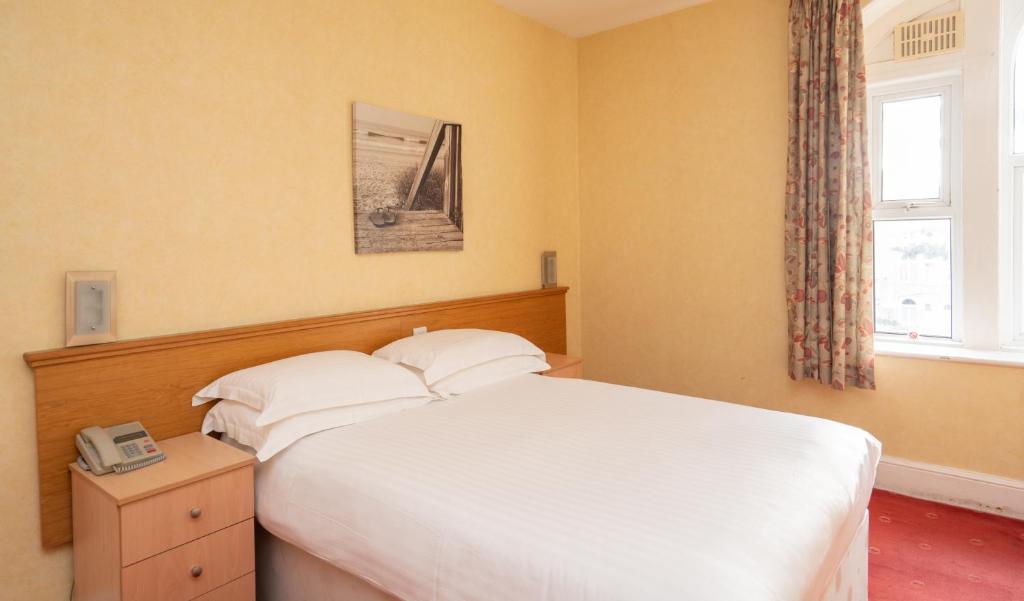 a bedroom with a white bed and a window at Lauriston Hotel in Weston-super-Mare