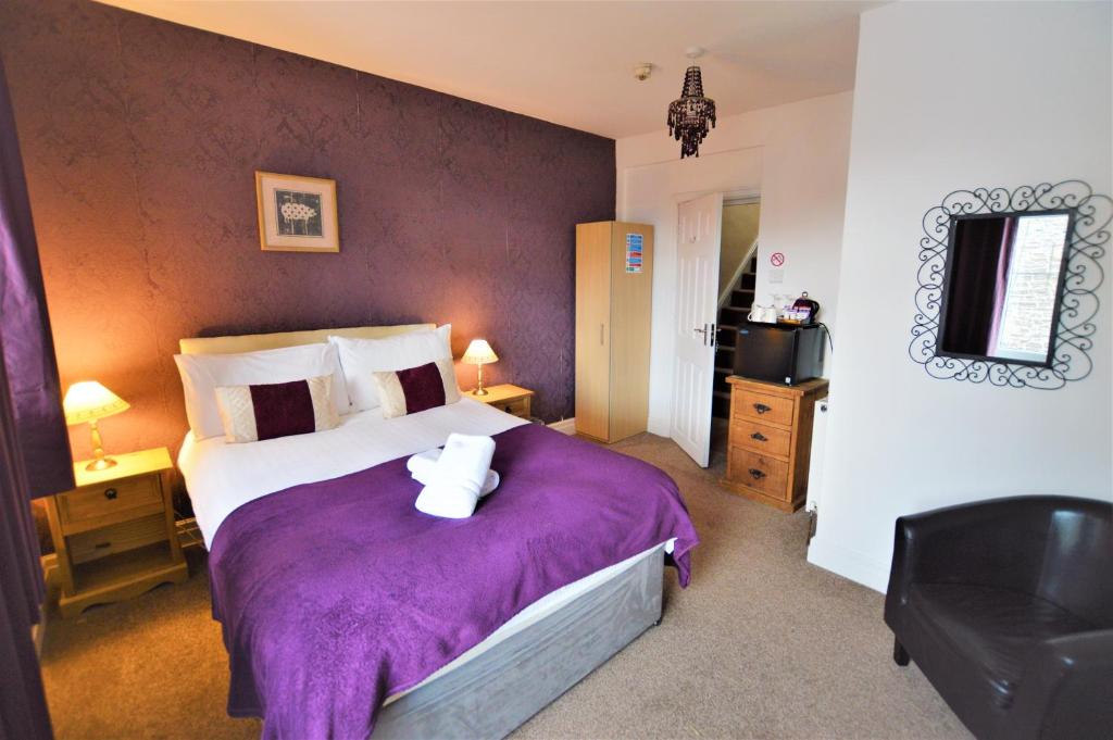a bedroom with a large bed with a purple blanket at All Seasons Rest in Windermere