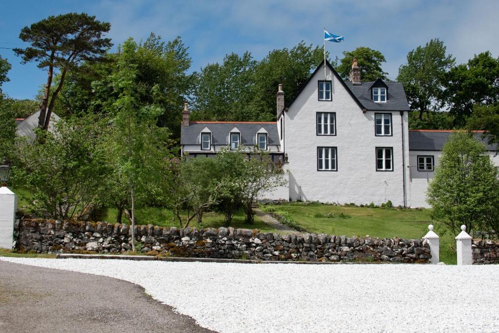 a large white house with a stone wall at The Albannach in Lochinver