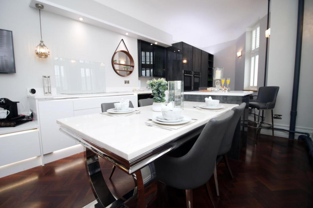 uma cozinha com uma grande mesa branca e cadeiras em The Clyne at Utopia Penthouse by MGroupSA em Swansea