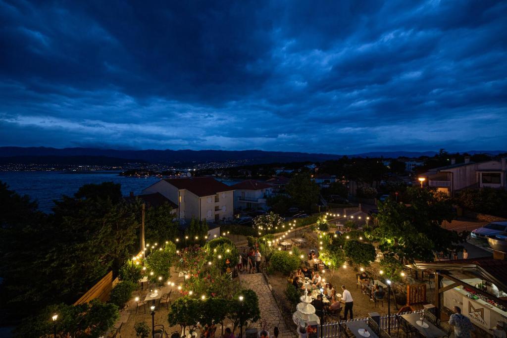 a group of people walking down a street at night at Meliores Rooms in Šilo