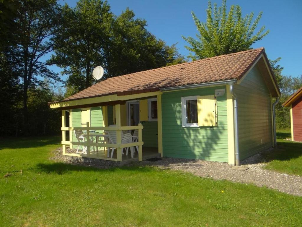 un cobertizo verde y amarillo con un banco en el patio en Chalet Campanules 37, en Mélisey