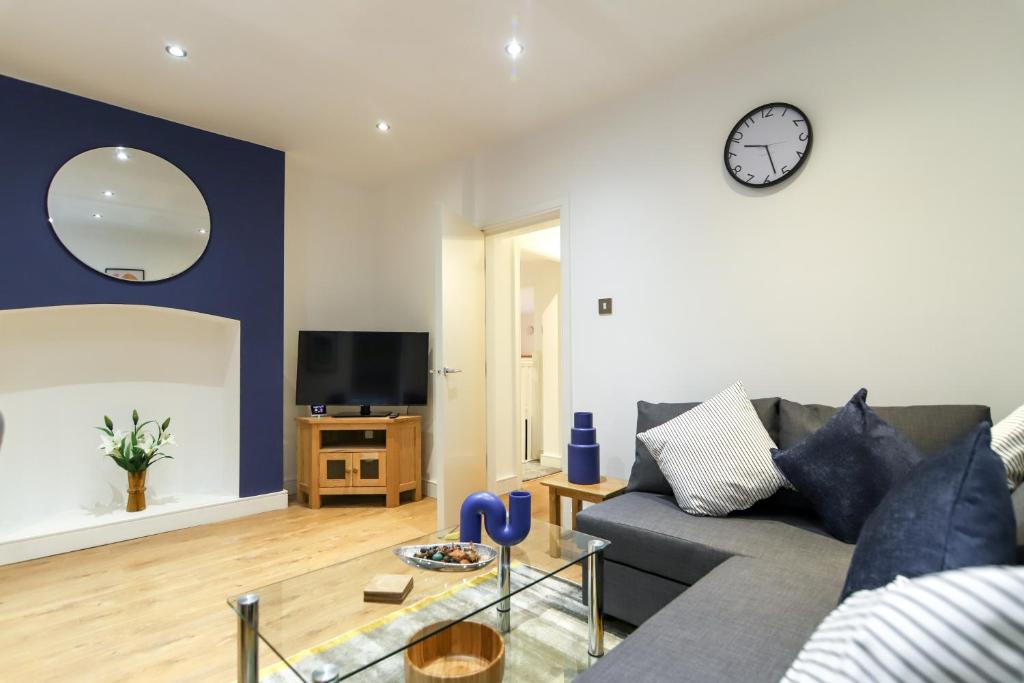 a living room with a couch and a clock on the wall at New- Modern 2br Apt Wifi Sleep5 City Centre in Sheffield