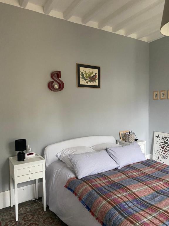 a white bedroom with a bed and a night stand at Suite&amp;Caux 1 in Cany-Barville