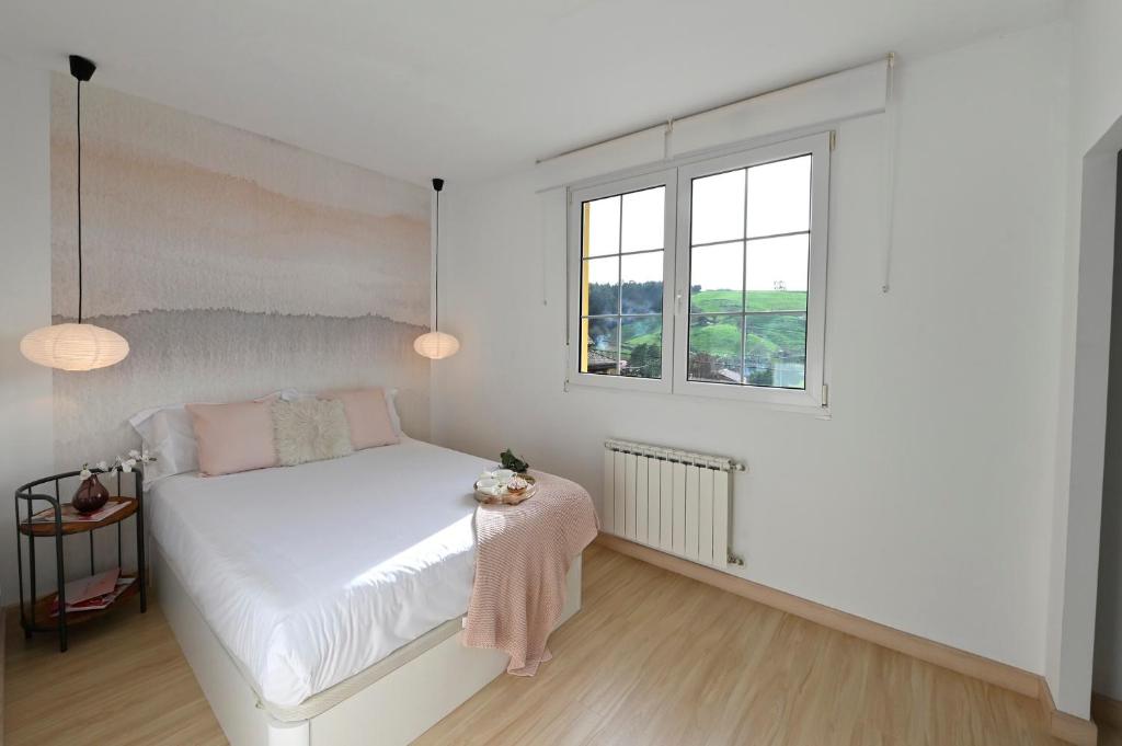 a white bedroom with a bed and a window at Casa con encanto entre el mar y la montaña, en el corazon de CANTABRIA in Puente Arce