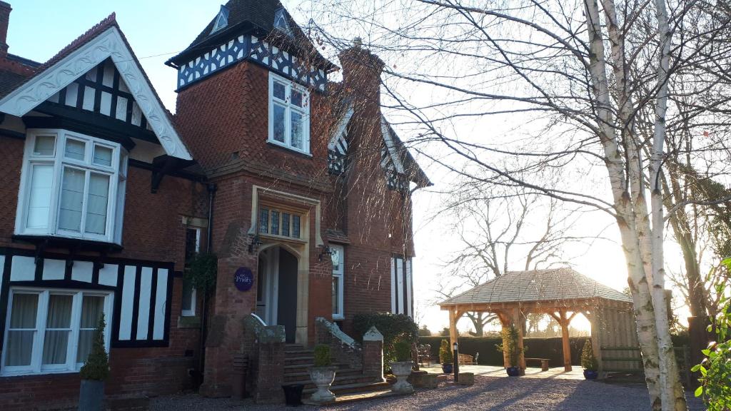 una gran casa de ladrillo con un cenador frente a ella en The Priory en Hereford