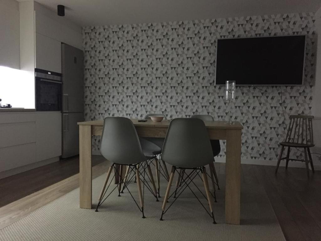 a dining room table with chairs and a television on a wall at Apartment Tarasy centrum in Siemiatycze