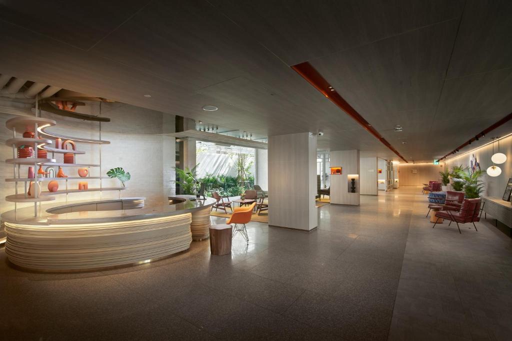 A large contemporary lobby with a sculptural reception desk, lounge seating and a long corridor.