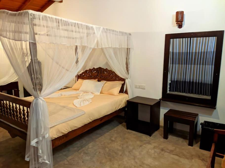 Calm House - Nature inspired private stay Mirissa في ميريسا: غرفة نوم مع سرير مظلة ونافذة