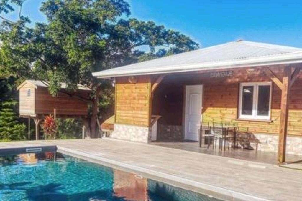 una casa con piscina di fronte a una casa di Magnifique maison en bois avec piscine a Sainte-Anne