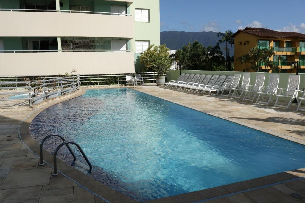 a large swimming pool with chairs and a building at Doce Lar de Bertioga frente ao Mar in Bertioga