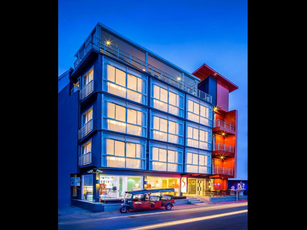 a building with a red car parked in front of it at Solo Express Sukhumvit 81 in Bangkok