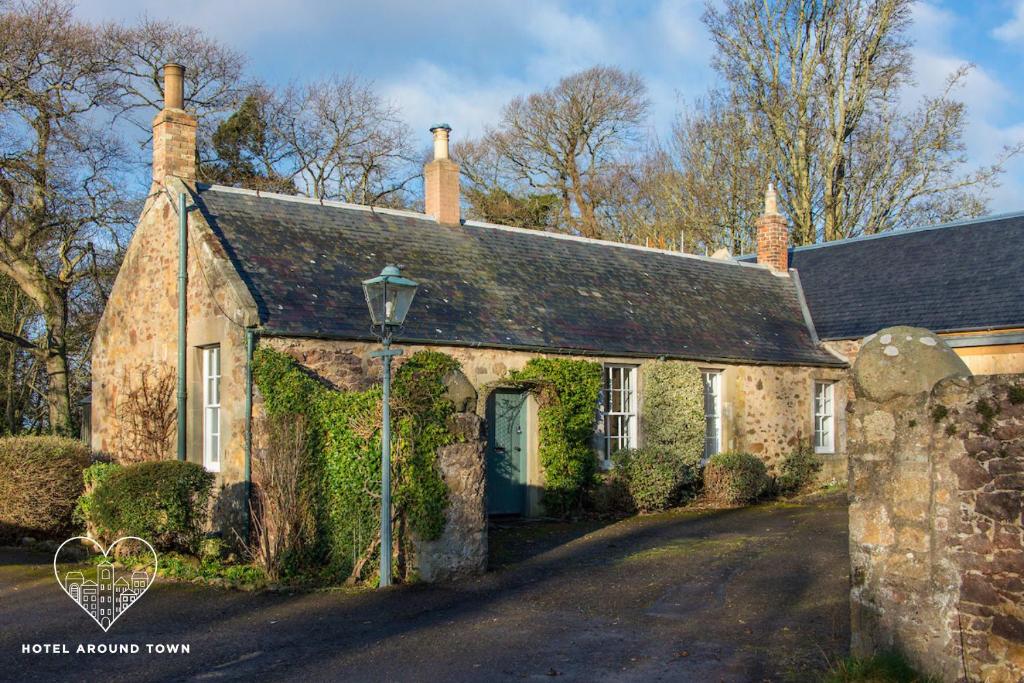 una vieja casa de piedra con hiedra creciendo en ella en Stunning Stables Cottage in East Lothian Country Estate, en North Berwick