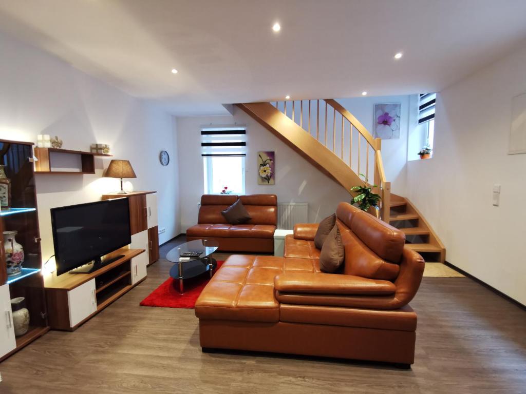 a living room with a brown leather couch and a staircase at Amys Ferienwohnungen Bad Harzburg in Bad Harzburg