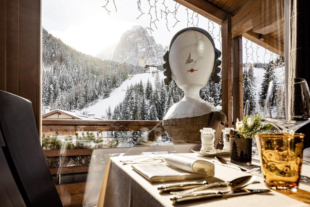 eine Schaufensterpuppe, die an einem Tisch vor einem Fenster sitzt in der Unterkunft ArtHotel Anterleghes - Gardenahotels in Wolkenstein in Gröden