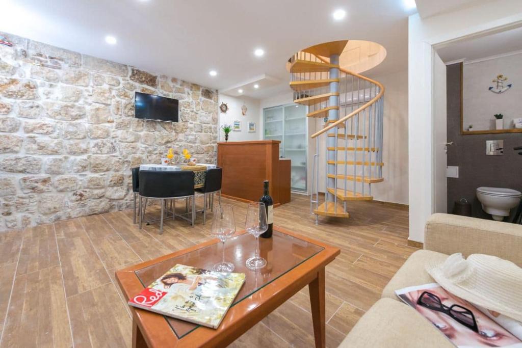a living room with a stone wall and a spiral staircase at New Apartment La Barca Old Town in Dubrovnik