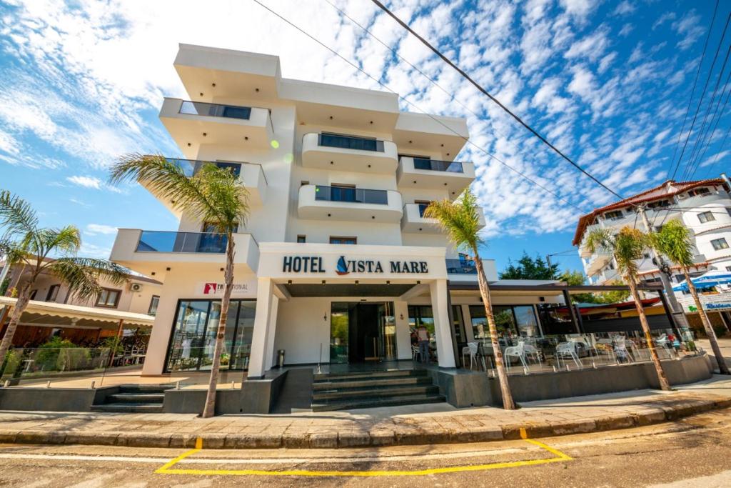 a building with palm trees in front of it at Hotel Vista Mare in Ksamil