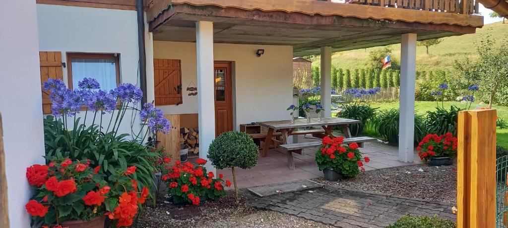 una casa con una mesa de picnic y algunas flores en gite au coin du feu à 25mn de Colmar au calme avec jardin clos, en Labaroche