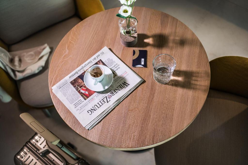 a wooden table with a newspaper and a glass of water at MOOONS Vienna in Vienna
