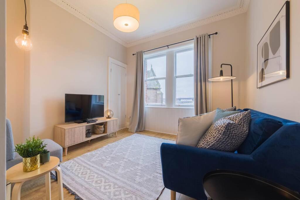 uma sala de estar com um sofá azul e uma televisão em The Trossachs Apartment em Stirling