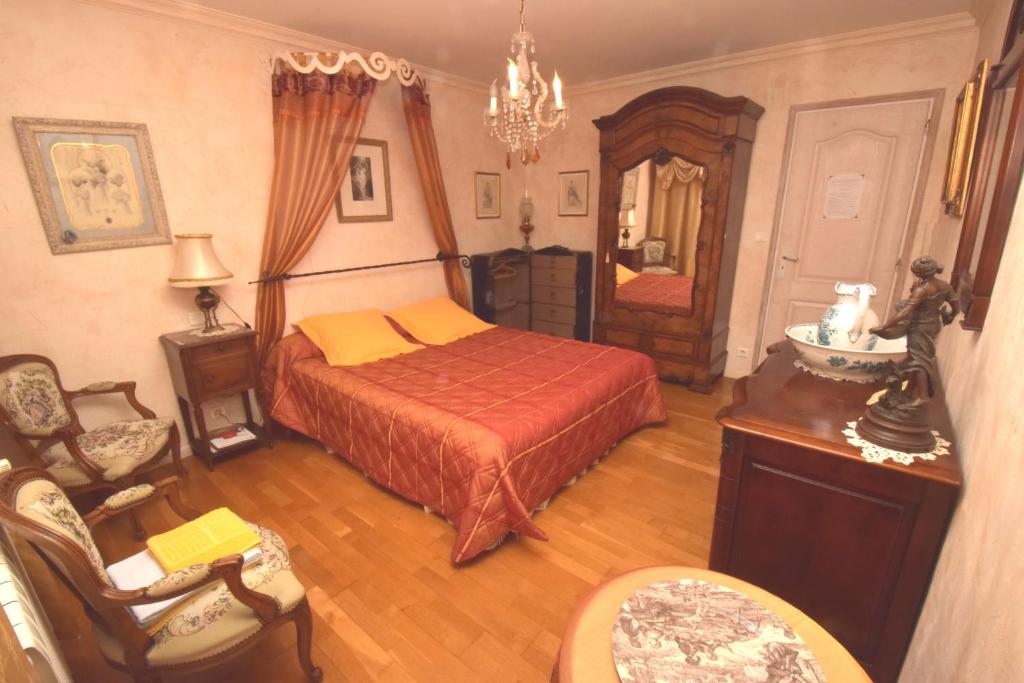 1 dormitorio con cama, silla y espejo en Autrefois La Modiste, en Saint-Clar
