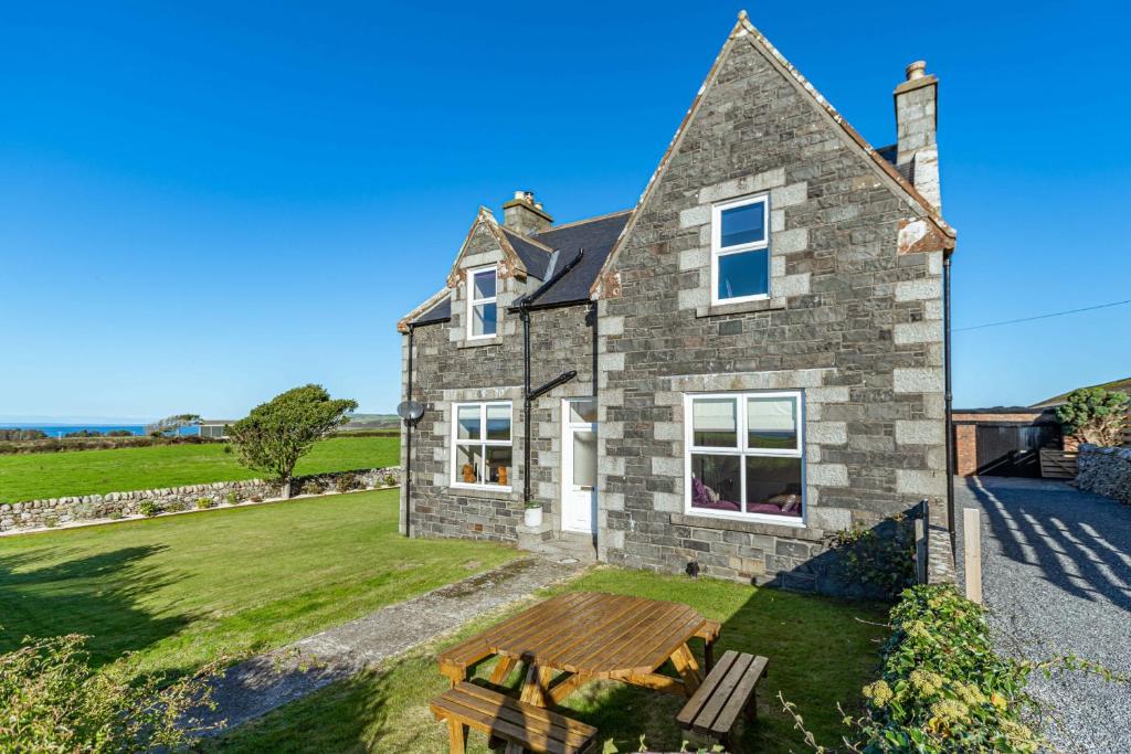 an old stone house with a bench in front of it at Dourie Farmhouse in Port William