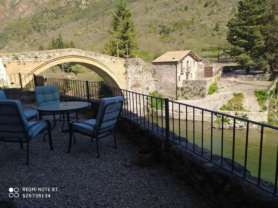 una mesa y sillas en un balcón con un puente en casa sobre rio Noguera Pallaresa, en Gerri
