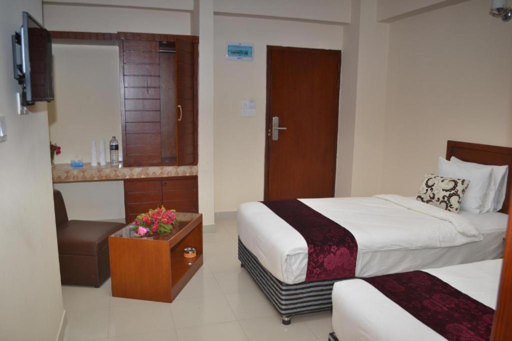 una habitación de hotel con 2 camas y una silla en Lighthouse Family Retreat, en Cox's Bazar
