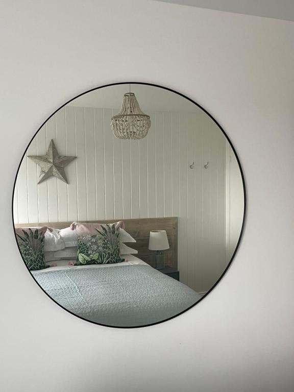 un miroir reflétant une chambre avec un lit dans l'établissement Westward 14 Polzeath, à Polzeath