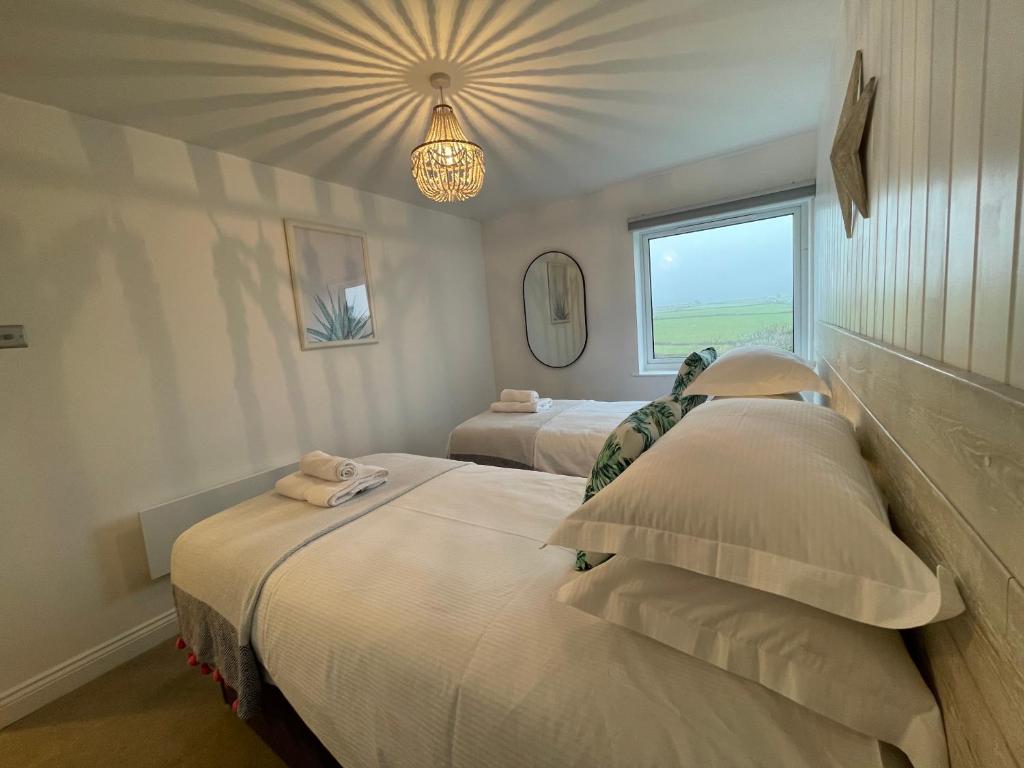a bedroom with two beds and a chandelier at Westward 14 Polzeath in Polzeath