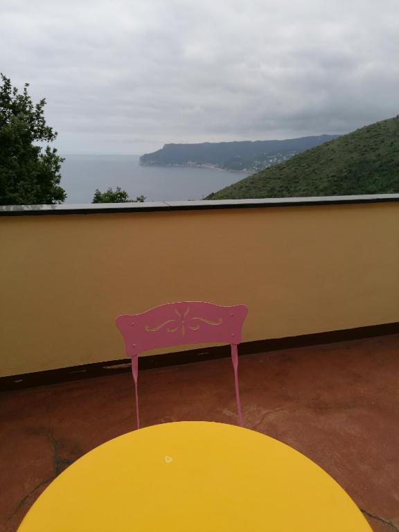 a pink chair sitting on a balcony with a yellow table at Oroverde in Bergeggi