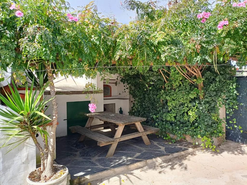 a wooden picnic table in front of a wall with flowers at Casa do Beco in Monsaraz