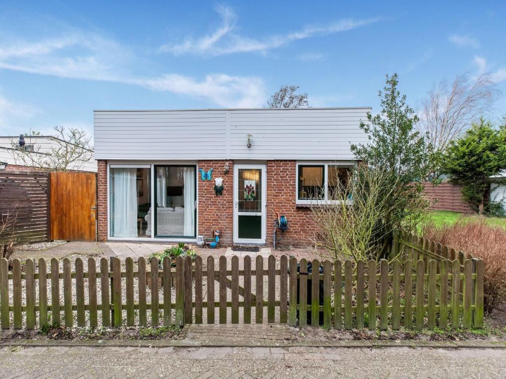 uma casa de tijolos com uma cerca em frente em Endearing Holiday Home in Noordwijkerhout with Garden BBQ em Noordwijkerhout