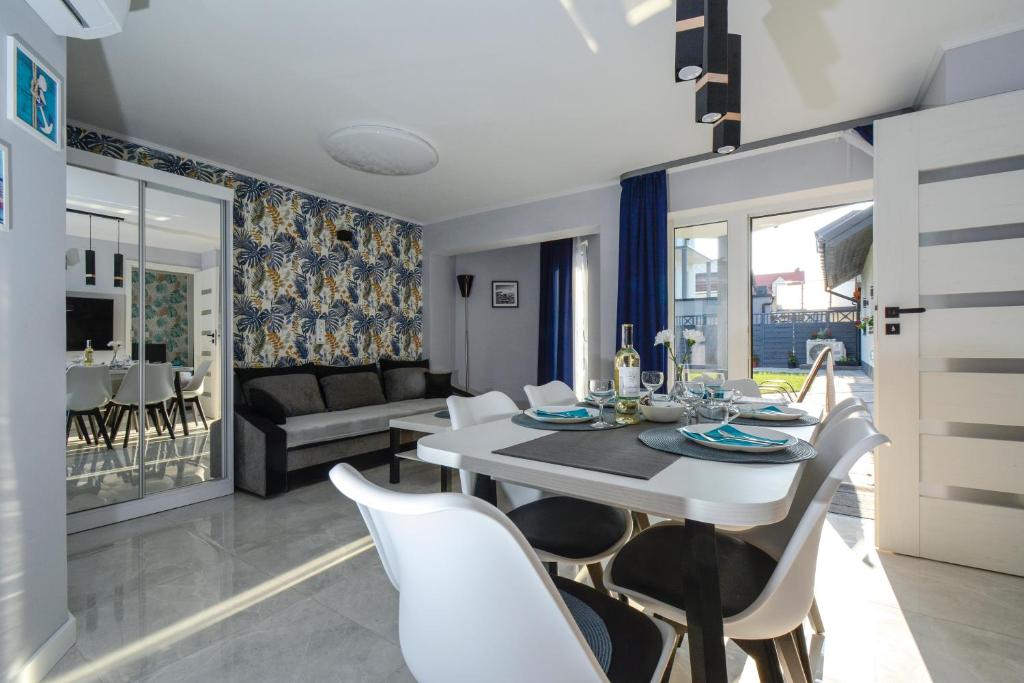 a dining room and living room with a white table and chairs at Apartamenty Prestige in Łeba