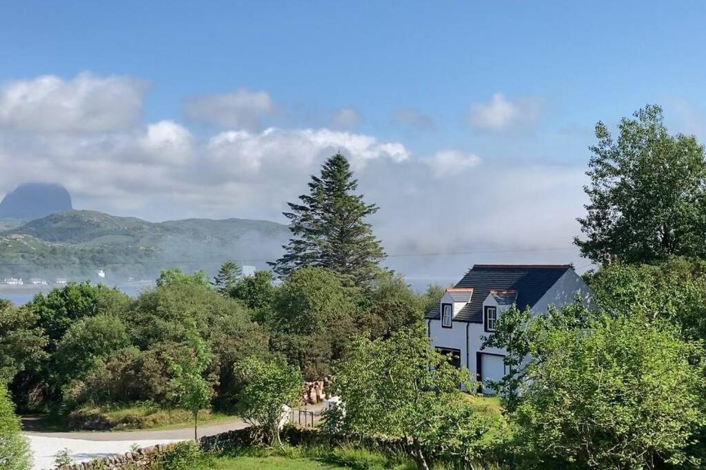 a house sitting on top of a hill with trees at The Coach House at The Albannach in Lochinver