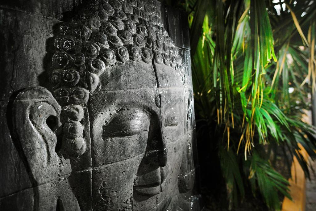 a stone pillar with a face on it next to a plant at El Taj Oceanfront and Beachside Condo Hotel in Playa del Carmen